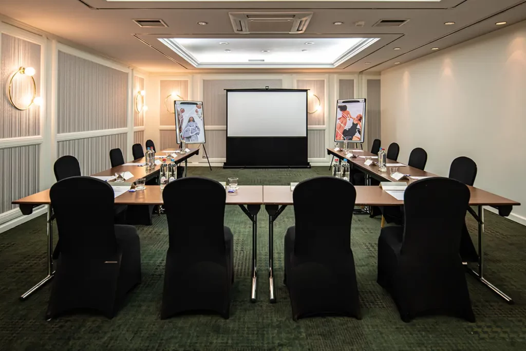 Der Basement Meetingraum mit Tischen und der U-Form und Stühlen rundherum.