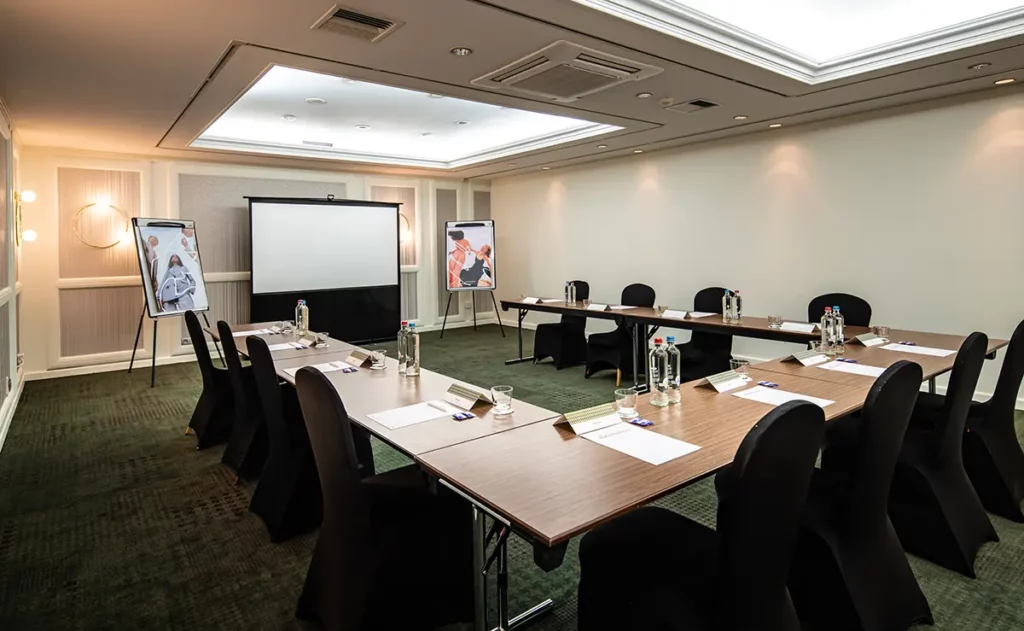 Der Basement Meetingraum mit Tischen und der U-Form und Stühlen rundherum.